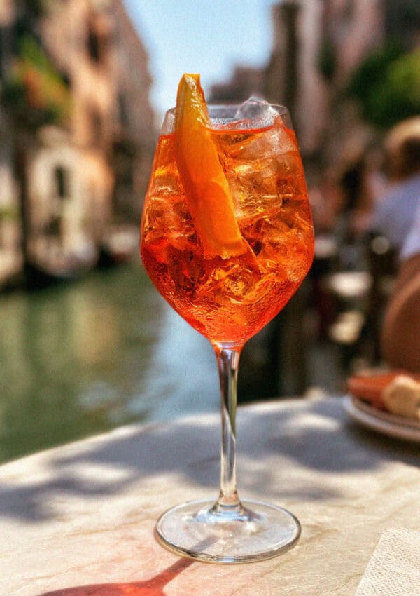 An Aperol spritz on a marble table by a Venetian canal