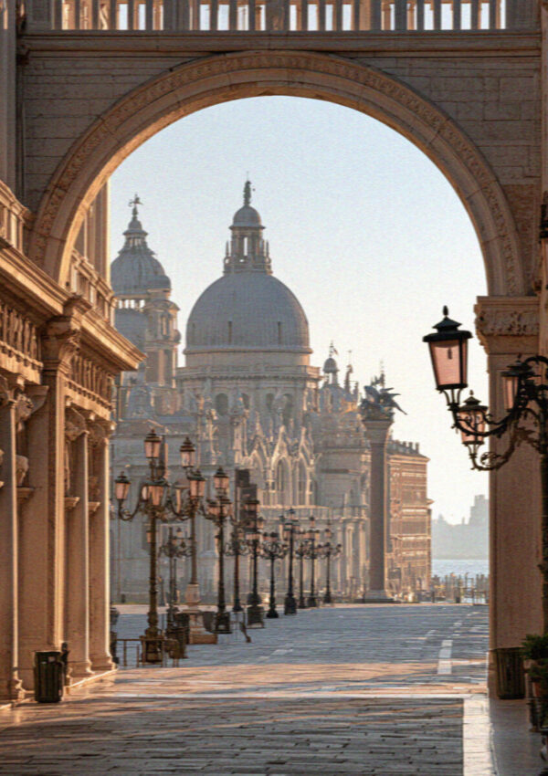 A domed Venetian church framed through a stone arcade and lamps at golden hour