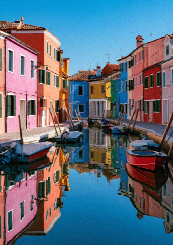 The painted houses of Burano reflected in a still canal