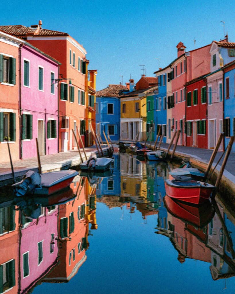 The painted houses of Burano reflected in a still canal