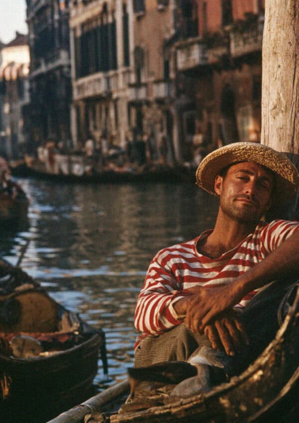 A Venetian gondolier in a striped shirt resting in his gondola