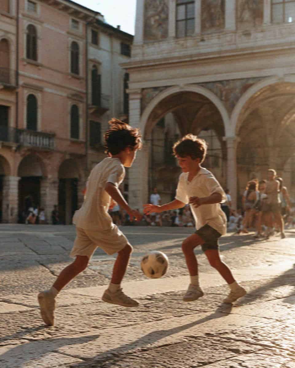 Two boys playing football in a Verona piazza at golden hour