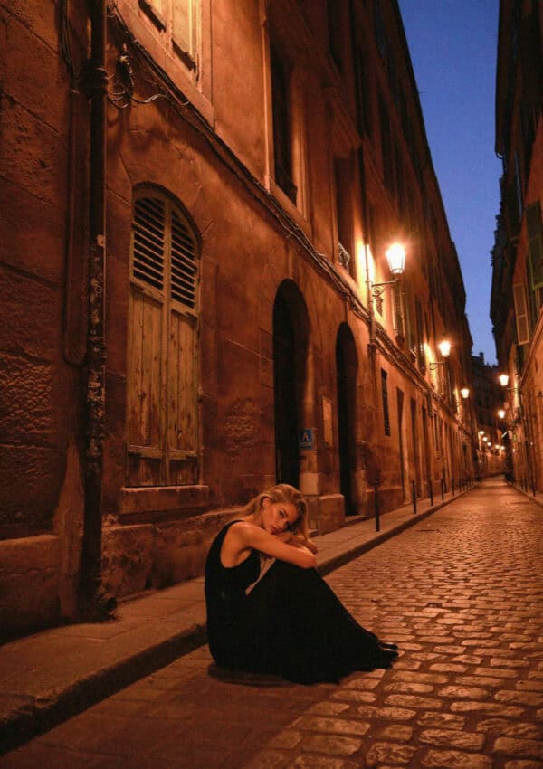 An elegant woman on a lamplit Verona lane at night