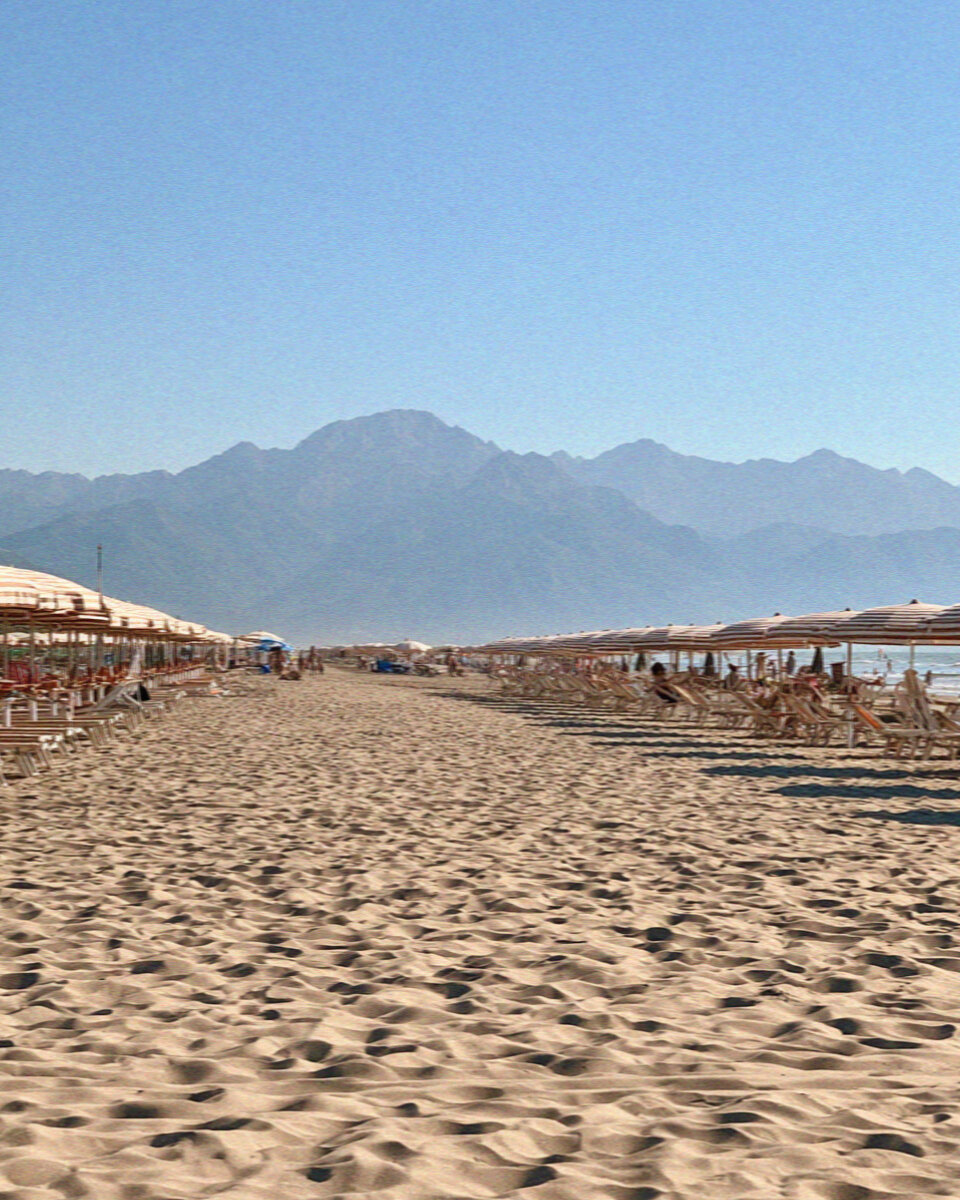 The sandy beach of Viareggio with rows of colourful umbrellas and the Apuan Alps behind