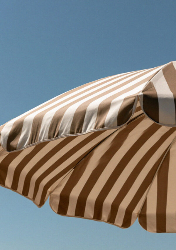 Close-up of taut brown and cream striped canvas on a beach umbrella against a hard blue sky on the Versilia coast in Tuscany