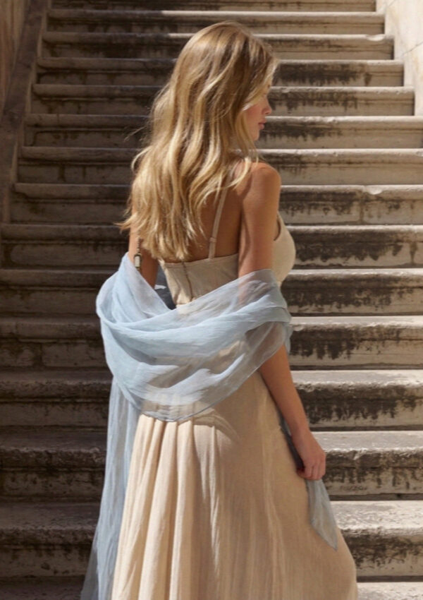 Victoria van der Berg with a pale wrap climbing worn stone stairs toward the light in Assisi
