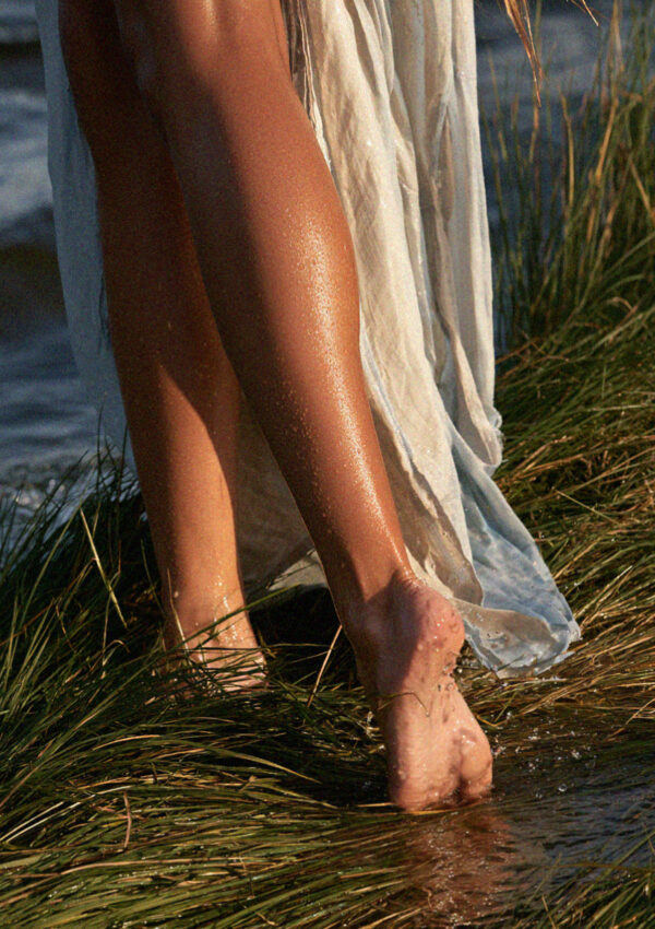 Victoria van der Berg wading at the edge of a warm Dolomites lake