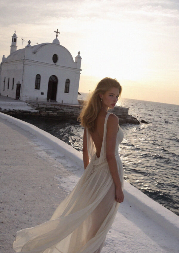 Victoria van der Berg walking toward the small white chapel on its rocky point on Ischia at dusk