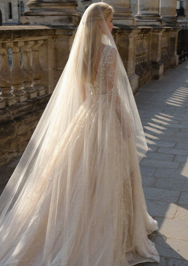 Victoria van der Berg in a long bridal veil walking a stone arcade on Lake Como