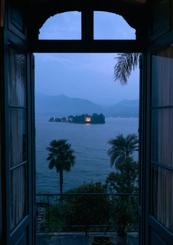 An arched window opening to Lake Maggiore at dusk