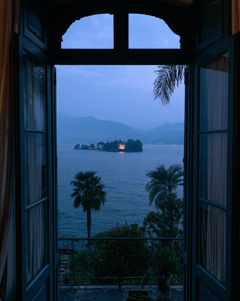 An arched window opening to Lake Maggiore at dusk