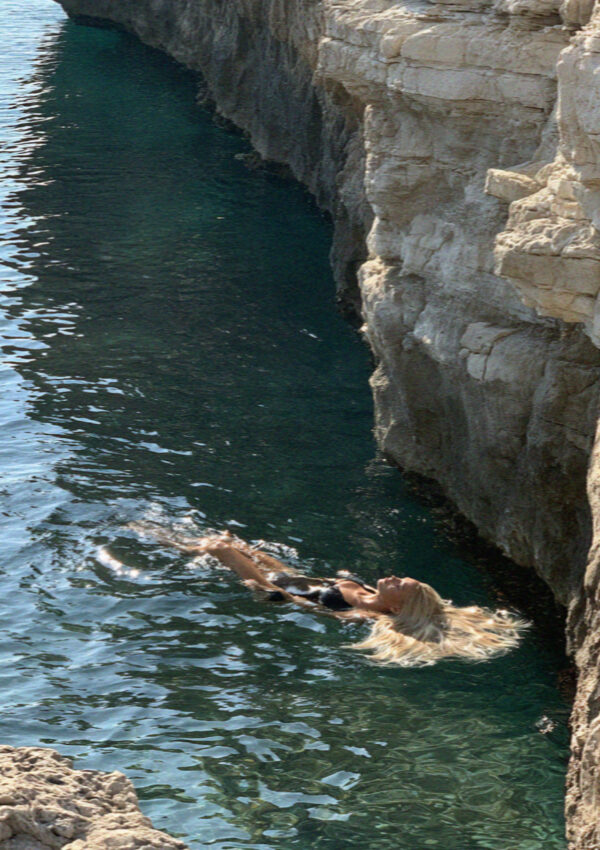 Victoria van der Berg floating in the clear water of the cove at Polignano a Mare