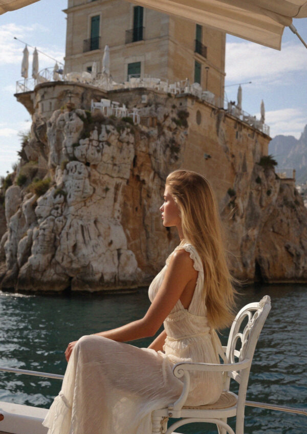 Victoria van der Berg seated on a terrace above the sea at Polignano a Mare