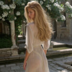 Victoria van der Berg in a white dress in a restored garden courtyard in Pompeii ringed by small columns with white oleander in flower