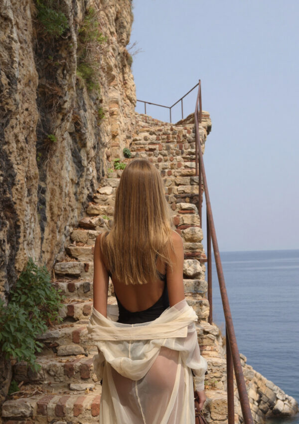 Victoria van der Berg descending stone steps cut into the cliff down to the sea in Sorrento