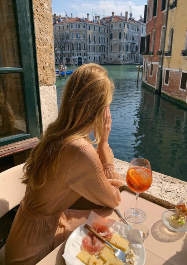 Victoria van der Berg with an Aperol spritz and cicchetti at a Venetian canal-side table