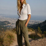 Victoria van der Berg in a white shirt and olive linen trousers looking out over the Bay of Naples from high on Vesuvius