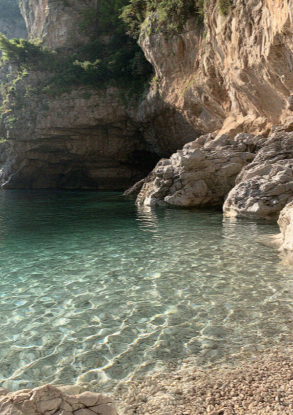 A hidden cove on the Amalfi Coast with clear water and no path down to it