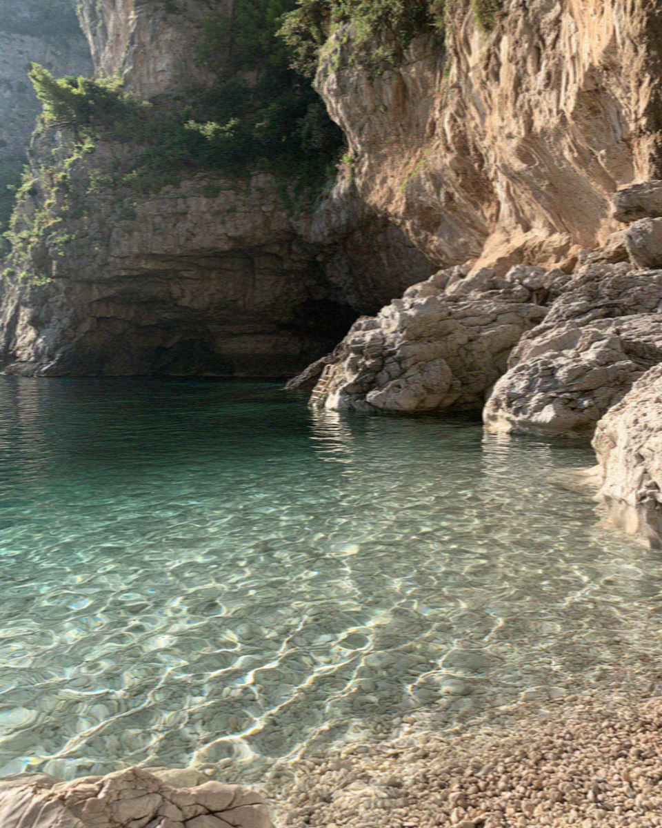 A hidden cove on the Amalfi Coast with clear water and no path down to it
