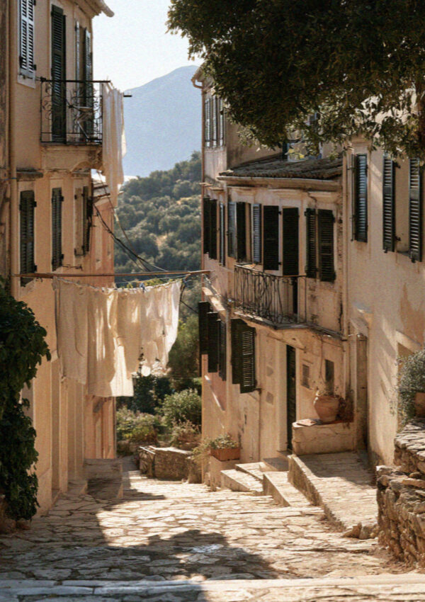A narrow lane of pastel houses in Corfu with washing strung between the shutters