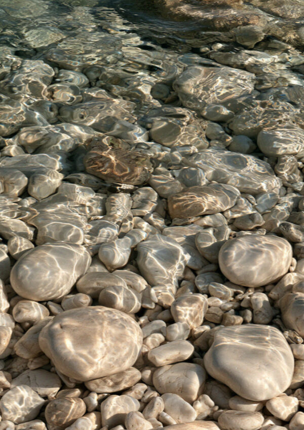 Pale pebbles under very clear shallow water on a Corfu beach