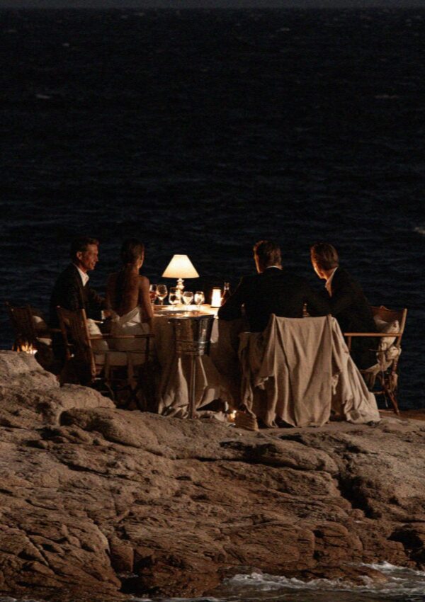 Four people at a table on the rocks above the water at night on the Costa Smeralda in Sardinia