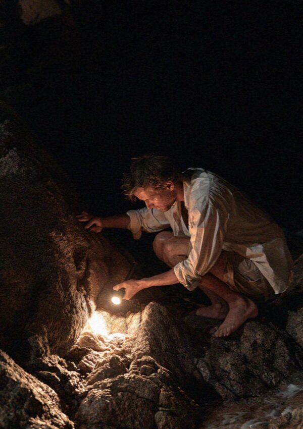 A man checking the lights sunk into the rocks with a torch on the Costa Smeralda in Sardinia