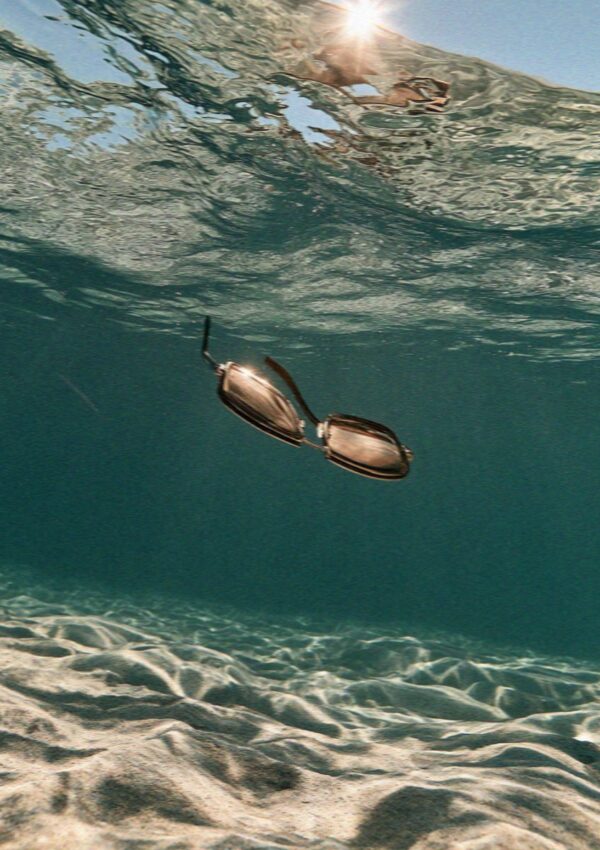 A pair of sunglasses sinking through clear water north of the Costa Smeralda in Sardinia