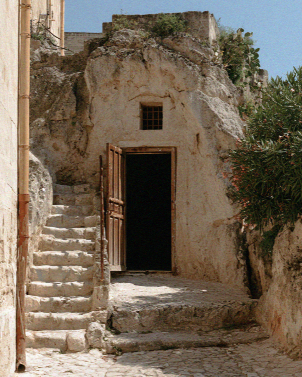 An open cave-house doorway in Matera, dark and cool against the sunlit stone