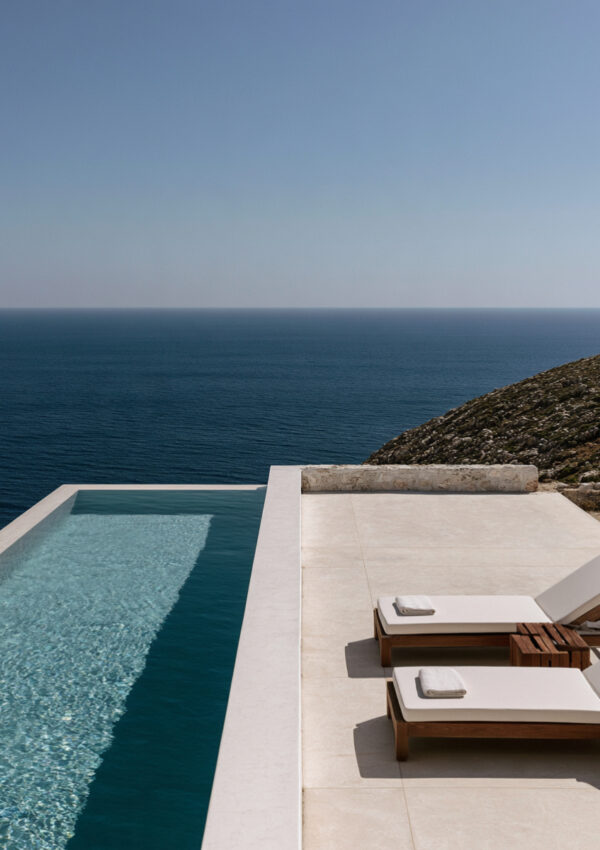 A white infinity pool and two loungers on a terrace above the open Aegean on Mykonos