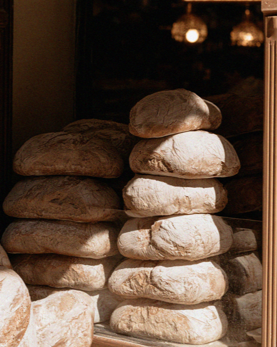 Stacked rustic loaves of bread in a bakery window
