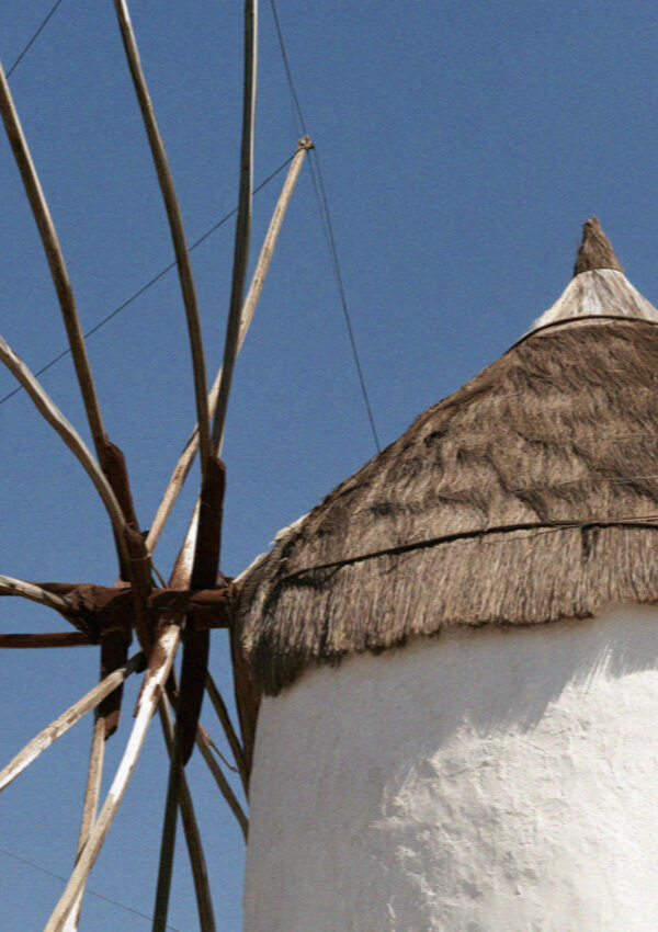 Close detail of a thatched windmill cap and wooden vanes against a blue sky in Mykonos