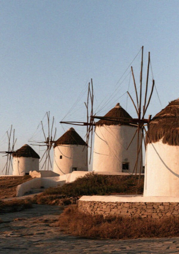 A row of thatched whitewashed windmills on the hill at Mykonos in golden evening light