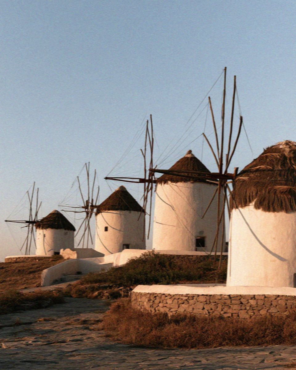 A row of thatched whitewashed windmills on the hill at Mykonos in golden evening light