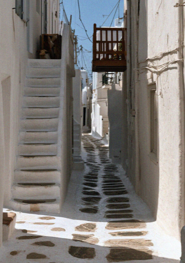 A narrow Mykonos lane with whitewash painted over the flagstone paving and a white outdoor stair