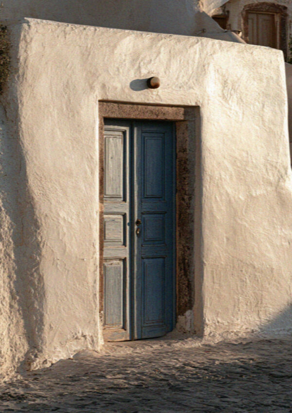 A blue door set in a whitewashed wall in Santorini