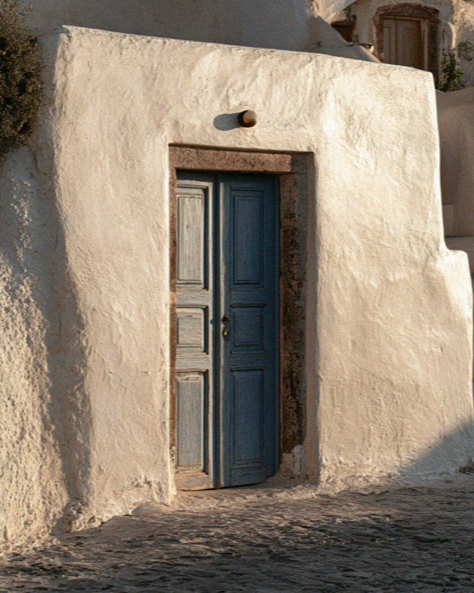 A blue door set in a whitewashed wall in Santorini