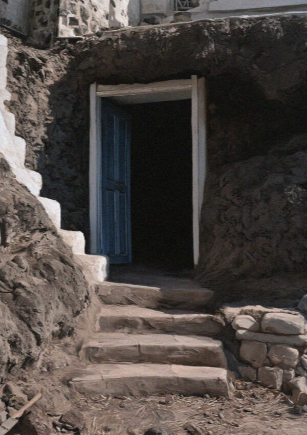A blue door at the top of stone steps opening into a cave house cut into the rock in Santorini