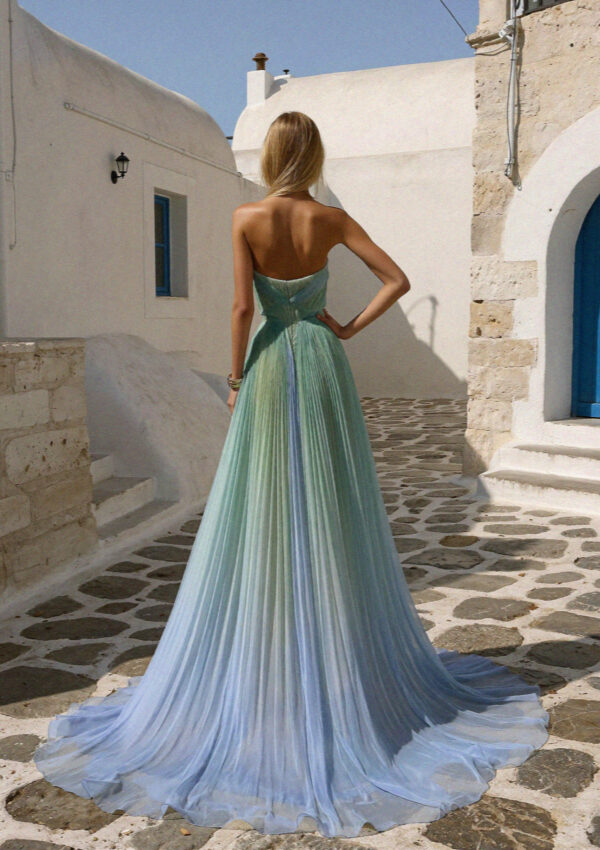 Victoria seen from behind in a green and blue pleated gown in a Megalochori lane