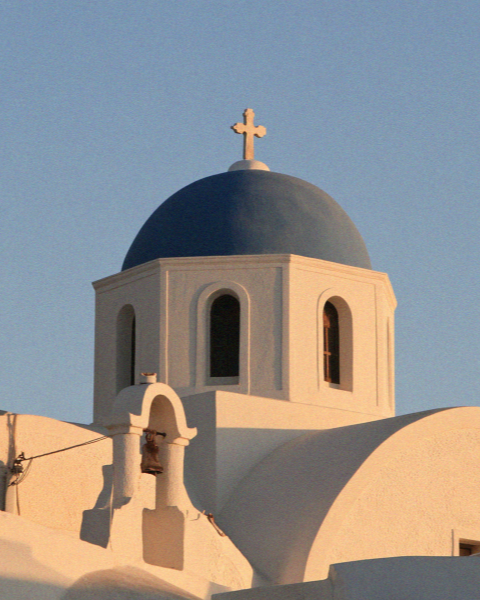 A blue-domed church in Santorini catching the last of the afternoon light