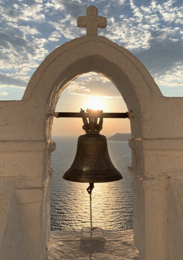 A church bell in Santorini framed against the evening sun