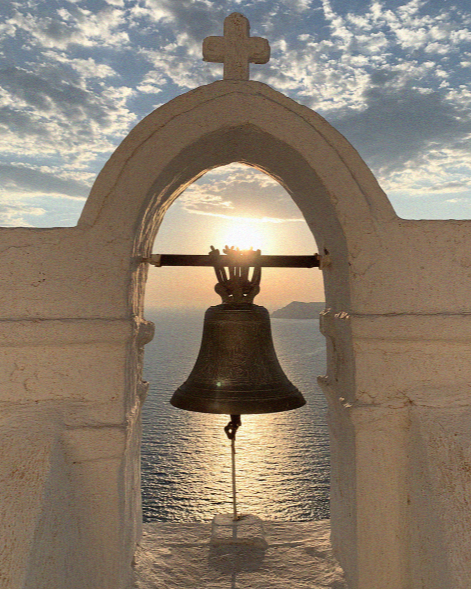 A church bell in Santorini framed against the evening sun