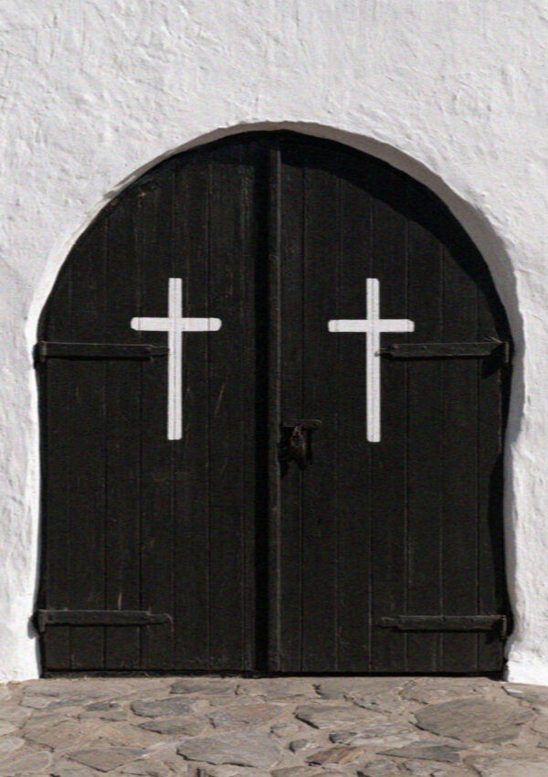 Black arched church doors painted with two white crosses in a Santorini village