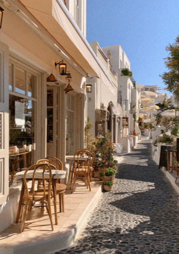 Empty cafe tables in a whitewashed lane in Santorini