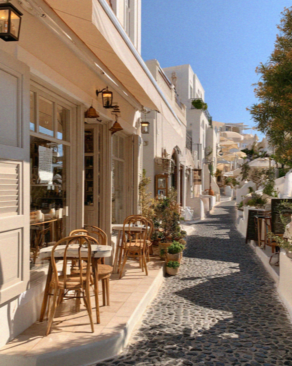 Empty cafe tables in a whitewashed lane in Santorini