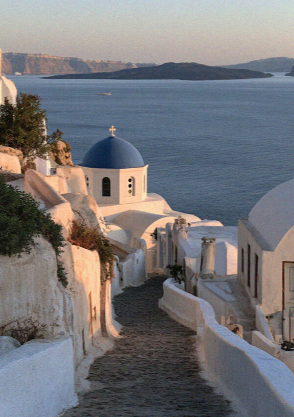 An empty whitewashed lane above the blue domes in Santorini