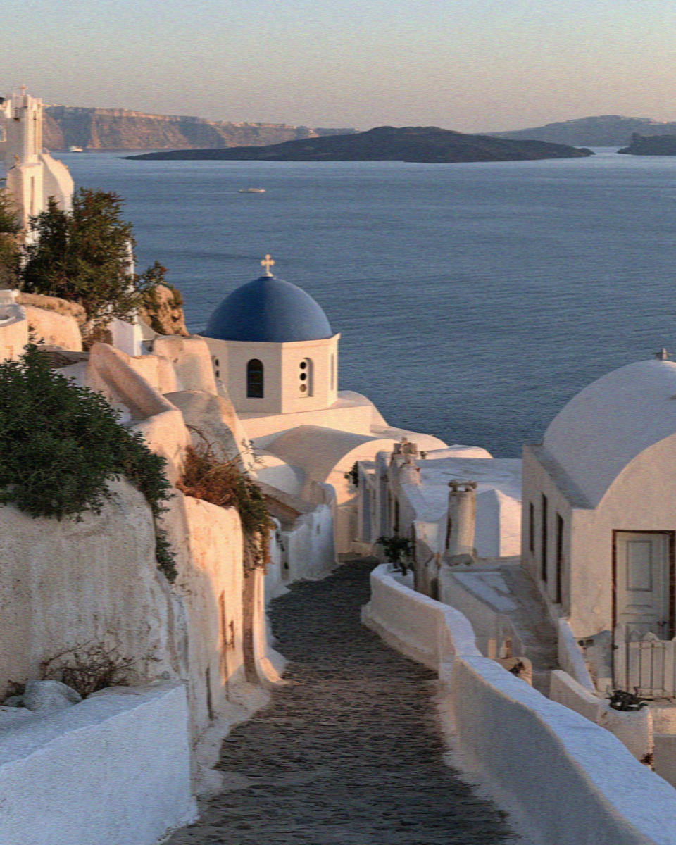 An empty whitewashed lane above the blue domes in Santorini
