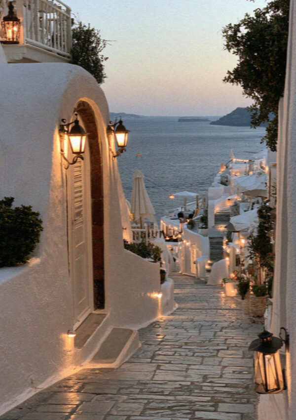 Lanterns lit in a whitewashed lane in Santorini at dusk