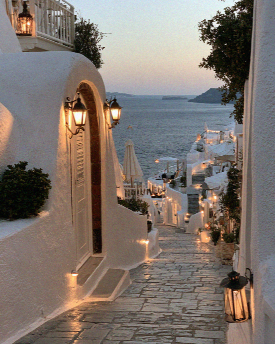Lanterns lit in a whitewashed lane in Santorini at dusk