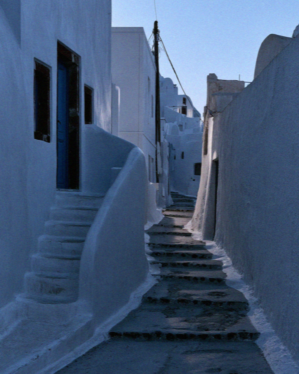 An empty whitewashed lane and steps in Megalochori, Santorini, at blue hour